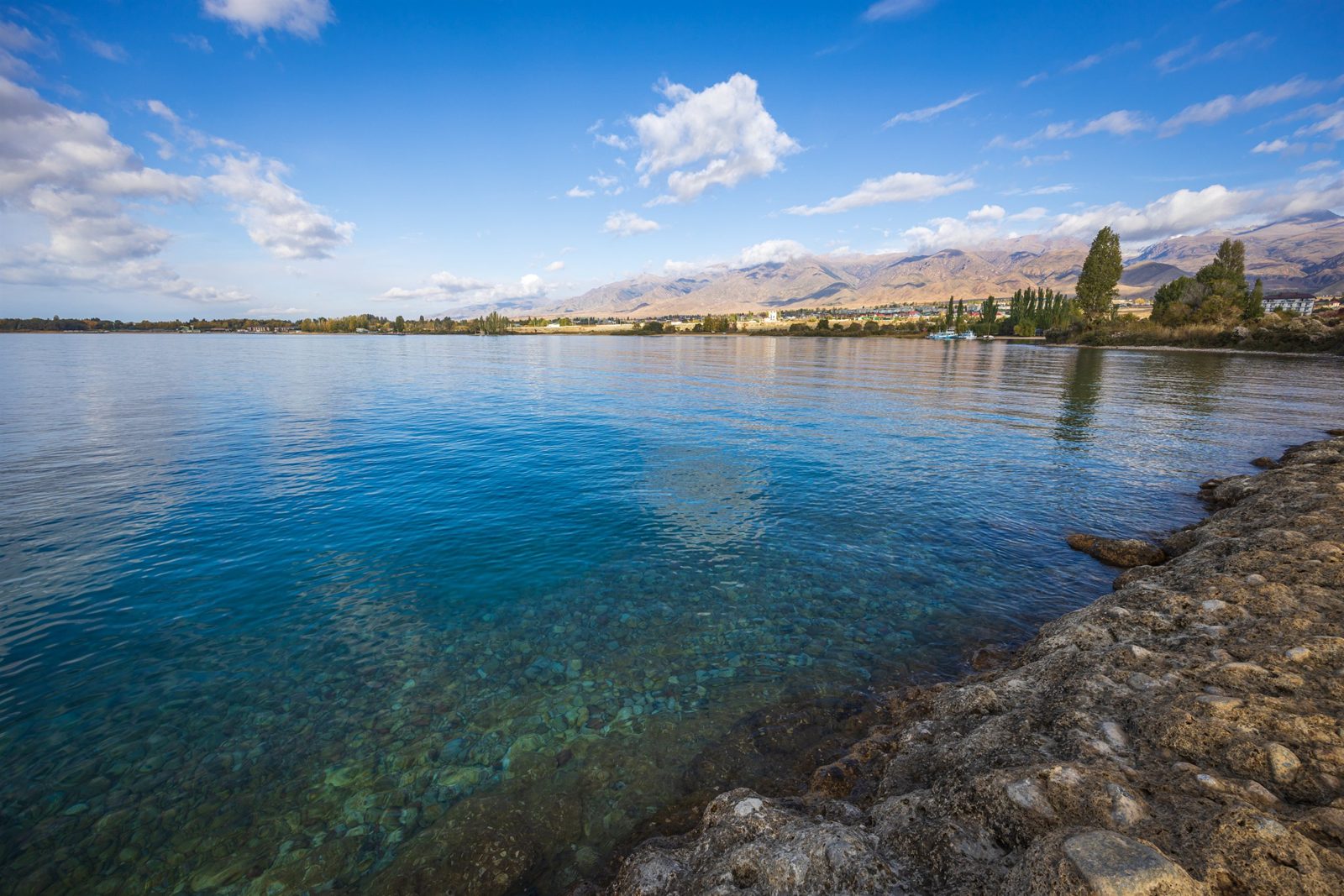 Прозрачная вода озера Иссык-Куль и горы на горизонте