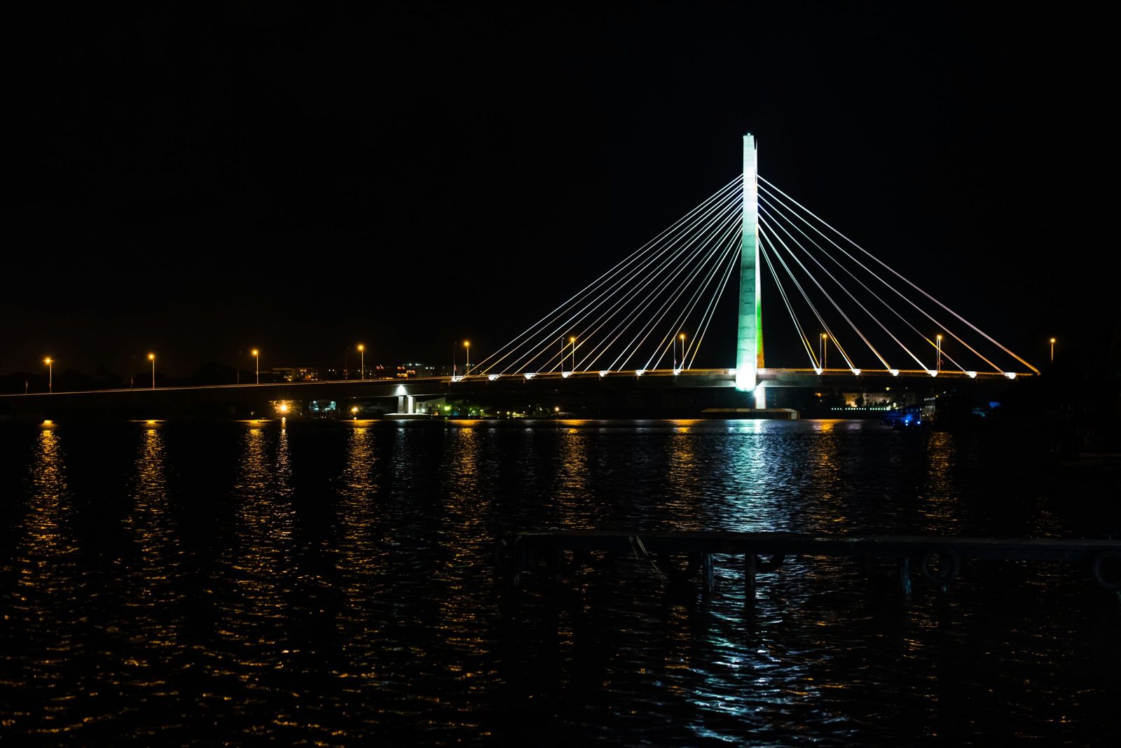 Вантовый мост Лекки-Икойи в ночной подсветке над водой
